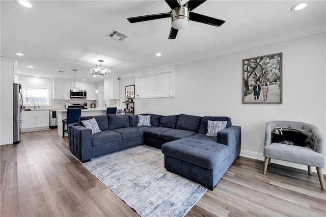 813 Cynthia Ave, Metairie, LA 70003 - living room with recessed lighting, a chandelier, ornamental molding, light wood-style flooring, and ceiling fan