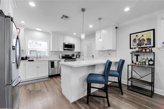 813 Cynthia Ave, Metairie, LA 70003 - kitchen with appliances with stainless steel finishes, wood finished floors, white cabinetry, tasteful backsplash, and recessed lighting