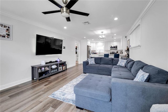 813 Cynthia Ave, Metairie, LA 70003 - living area with recessed lighting, a chandelier, a ceiling fan, light wood-style flooring, and crown molding