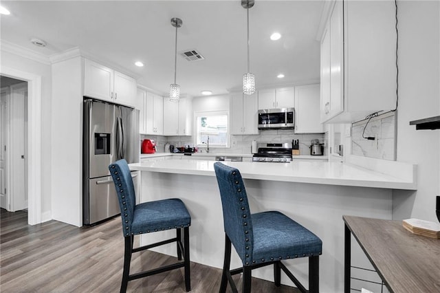 813 Cynthia Ave, Metairie, LA 70003 - kitchen with stainless steel appliances, recessed lighting, wood finished floors, a peninsula, and white cabinetry
