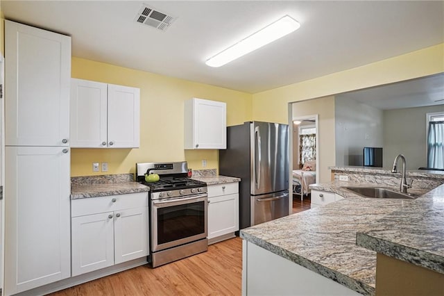 3713 Lausat St, Metairie, LA 70001 - kitchen with stainless steel appliances, light wood-style flooring, white cabinetry, and light stone countertops