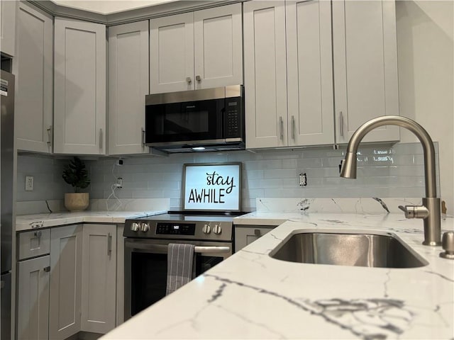 1201 Canal St Unit 216, New Orleans, LA 70112 - kitchen with stainless steel appliances, gray cabinets, tasteful backsplash, and light stone counters