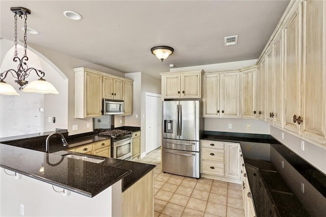 314 Spartan Loop, Slidell, LA 70458 - kitchen with appliances with stainless steel finishes, cream cabinetry, light tile patterned flooring, decorative light fixtures, and arched walkways