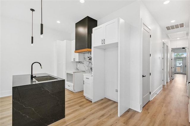 1871 N Roman St, New Orleans, LA 70116 - kitchen with light wood finished floors, white cabinets, pendant lighting, custom exhaust hood, and recessed lighting