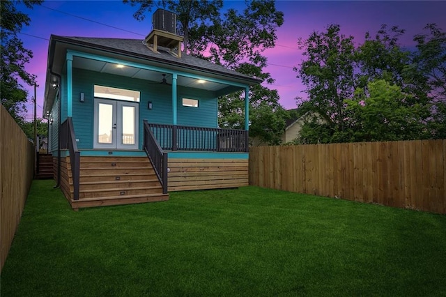 1871 N Roman St, New Orleans, LA 70116 - back of property at dusk with a fenced backyard, stairway, and a ceiling fan