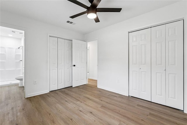 1828 San Francisco Rd, La Place, LA 70068 - unfurnished bedroom featuring wood finished floors, ensuite bathroom, two closets, and ceiling fan