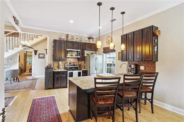 626 Independence St, New Orleans, LA 70117 - kitchen featuring stainless steel appliances, dark brown cabinetry, light wood-style flooring, ornamental molding, and recessed lighting