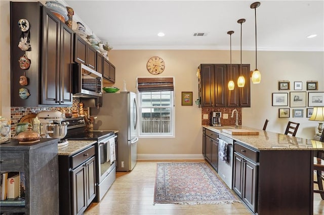 626 Independence St, New Orleans, LA 70117 - kitchen with appliances with stainless steel finishes, a peninsula, dark brown cabinets, decorative backsplash, and ornamental molding
