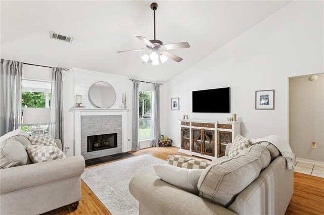 240 Emerald Crk W, Abita Springs, LA 70420 - living room featuring vaulted ceiling, a fireplace, a ceiling fan, and wood finished floors