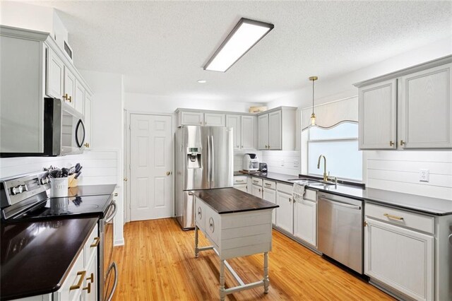 240 Emerald Crk W, Abita Springs, LA 70420 - kitchen with appliances with stainless steel finishes, dark countertops, gray cabinets, light wood-type flooring, and a textured ceiling
