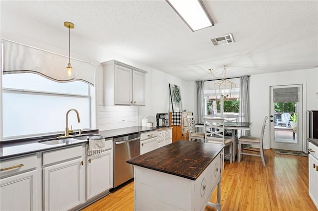 240 Emerald Crk W, Abita Springs, LA 70420 - kitchen featuring stainless steel dishwasher, a textured ceiling, light wood finished floors, a kitchen island, and decorative light fixtures