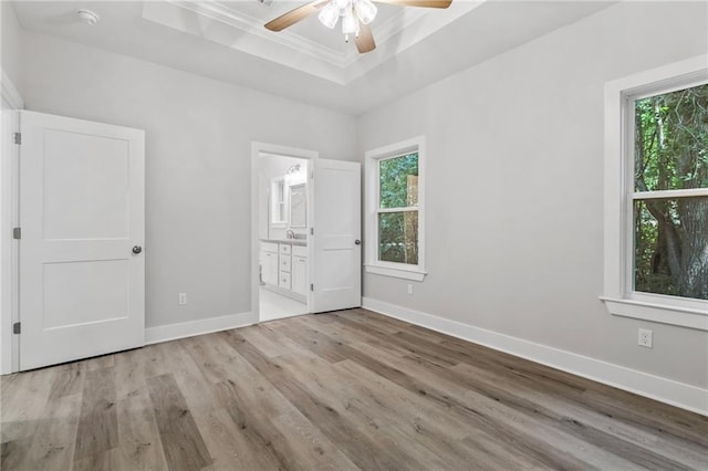 74446 Delta Ave, Covington, LA 70435 - unfurnished bedroom featuring a tray ceiling, multiple windows, wood finished floors, crown molding, and ensuite bathroom