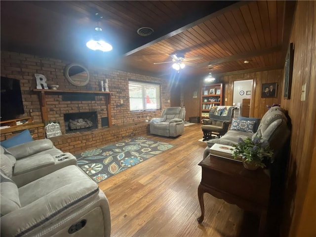 74258 N River Rd, Kentwood, LA 70444 - living room featuring brick wall, a brick fireplace, wooden walls, wood finished floors, and ceiling fan