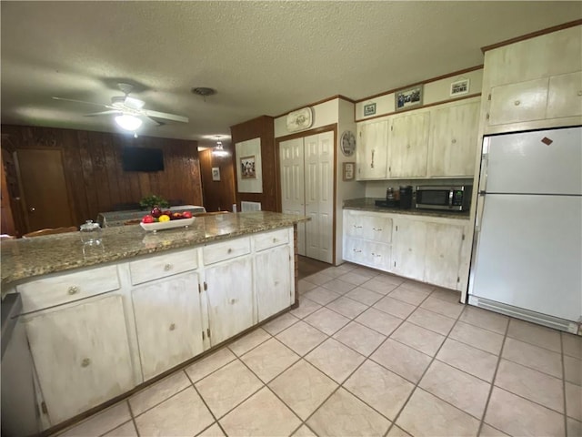 74258 N River Rd, Kentwood, LA 70444 - kitchen featuring freestanding refrigerator, stainless steel microwave, ceiling fan, a textured ceiling, and light tile patterned flooring