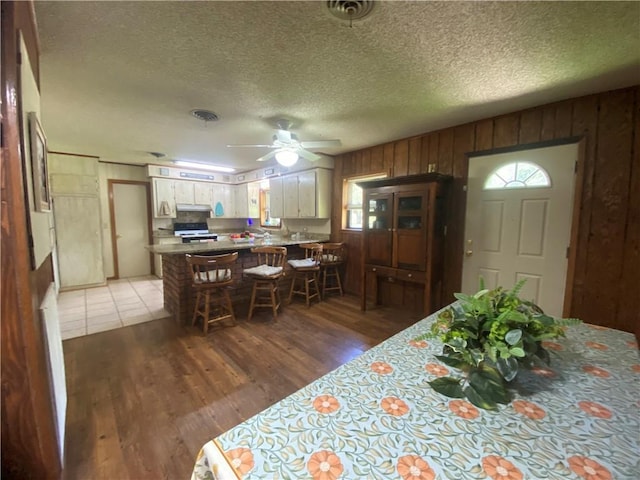 74258 N River Rd, Kentwood, LA 70444 - dining area with light wood-style flooring, a ceiling fan, wood walls, and a textured ceiling