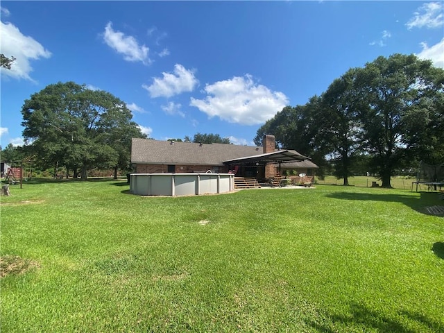 74258 N River Rd, Kentwood, LA 70444 - rear view of property featuring a trampoline, an outdoor pool, and a yard