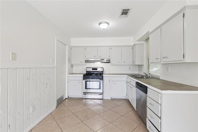 6501 Lafreniere St, Metairie, LA 70003 - kitchen with under cabinet range hood, appliances with stainless steel finishes, a wainscoted wall, light tile patterned floors, and white cabinetry