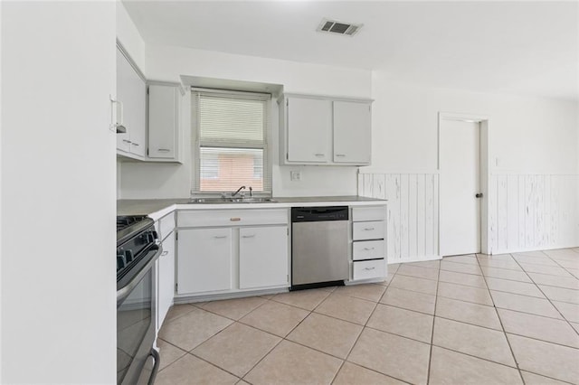 6501 Lafreniere St, Metairie, LA 70003 - kitchen with stainless steel appliances, wainscoting, light countertops, light tile patterned floors, and white cabinets