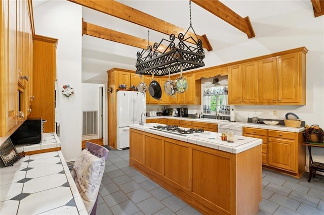 19632 Carol Morgan Rd, Franklinton, LA 70438 - kitchen with white appliances, tile counters, a kitchen island, light tile patterned floors, and beam ceiling