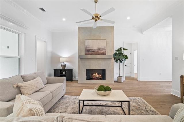 1169 Fox Sparrow Loop, Madisonville, LA 70447 - living room featuring wood finished floors, a ceiling fan, crown molding, a tiled fireplace, and recessed lighting