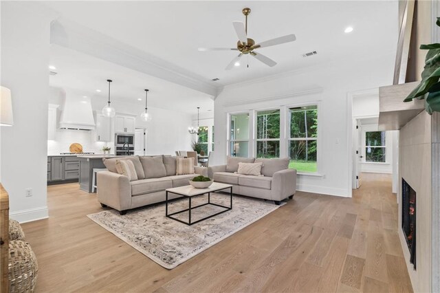 1169 Fox Sparrow Loop, Madisonville, LA 70447 - living area with ceiling fan, light wood-style flooring, a lit fireplace, recessed lighting, and a chandelier