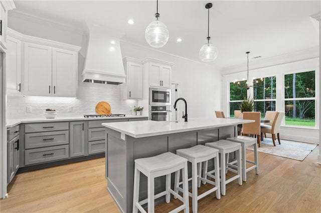 1169 Fox Sparrow Loop, Madisonville, LA 70447 - kitchen with gray cabinets, custom range hood, gas stovetop, light countertops, and backsplash