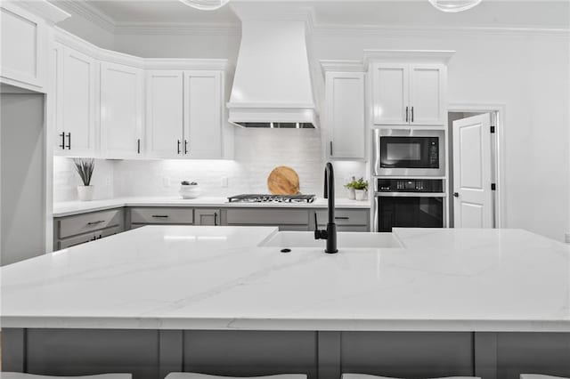 1169 Fox Sparrow Loop, Madisonville, LA 70447 - kitchen featuring appliances with stainless steel finishes, premium range hood, tasteful backsplash, light stone countertops, and crown molding