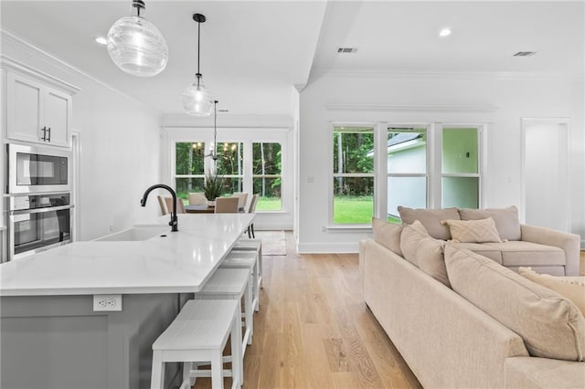1169 Fox Sparrow Loop, Madisonville, LA 70447 - kitchen with stainless steel oven, open floor plan, built in microwave, light wood-type flooring, and healthy amount of natural light