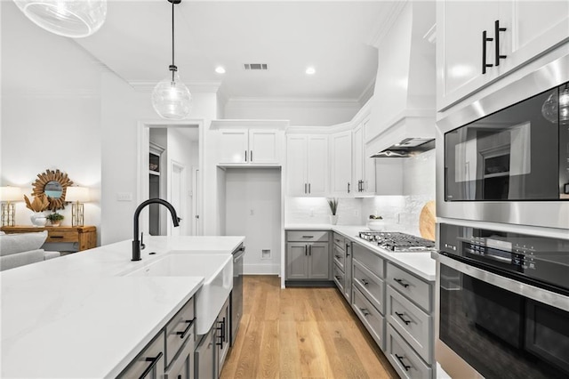 1169 Fox Sparrow Loop, Madisonville, LA 70447 - kitchen featuring appliances with stainless steel finishes, gray cabinets, light countertops, pendant lighting, and light wood-style floors