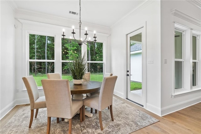 1169 Fox Sparrow Loop, Madisonville, LA 70447 - dining room featuring healthy amount of natural light, light wood-style floors, a chandelier, and ornamental molding