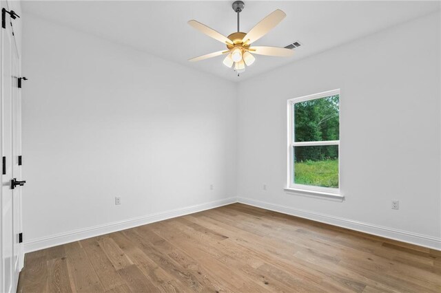 1169 Fox Sparrow Loop, Madisonville, LA 70447 - unfurnished room with wood finished floors, a ceiling fan, and a barn door