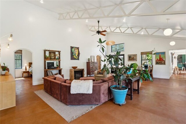 80695 Bob Baxter Rd, Bush, LA 70431 - living room featuring finished concrete flooring, plenty of natural light, high vaulted ceiling, arched walkways, and a ceiling fan