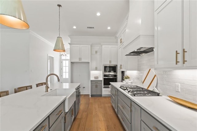 4141 Endor Loop, Mandeville, LA 70448 - kitchen featuring appliances with stainless steel finishes, custom exhaust hood, gray cabinetry, hanging light fixtures, and crown molding