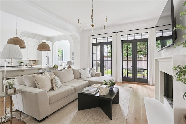 303 W William David Pkwy, Metairie, LA 70005 - living room featuring french doors, arched walkways, light wood-style flooring, a chandelier, and a fireplace