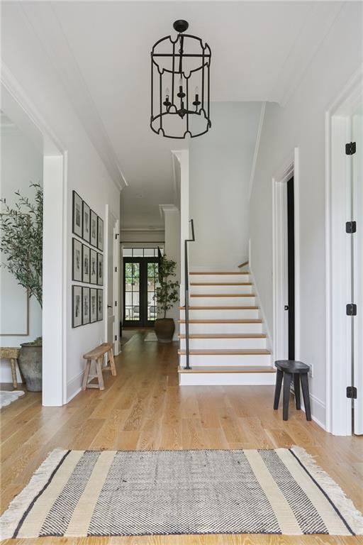 303 W William David Pkwy, Metairie, LA 70005 - entryway with french doors, stairway, wood finished floors, a chandelier, and ornamental molding