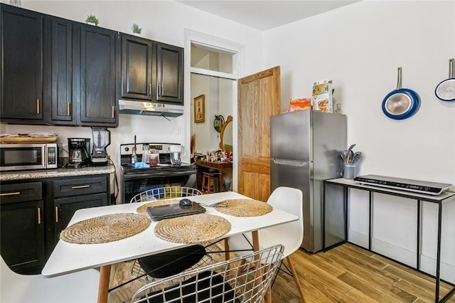 112830 N Roman St, New Orleans, LA 70116 - kitchen featuring appliances with stainless steel finishes, under cabinet range hood, light wood finished floors, and dark cabinetry
