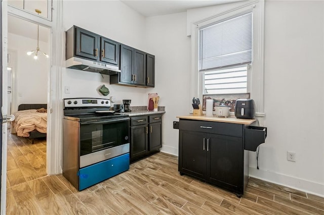 112830 N Roman St, New Orleans, LA 70116 - kitchen with stainless steel electric range, under cabinet range hood, light wood-style floors, light countertops, and dark cabinetry