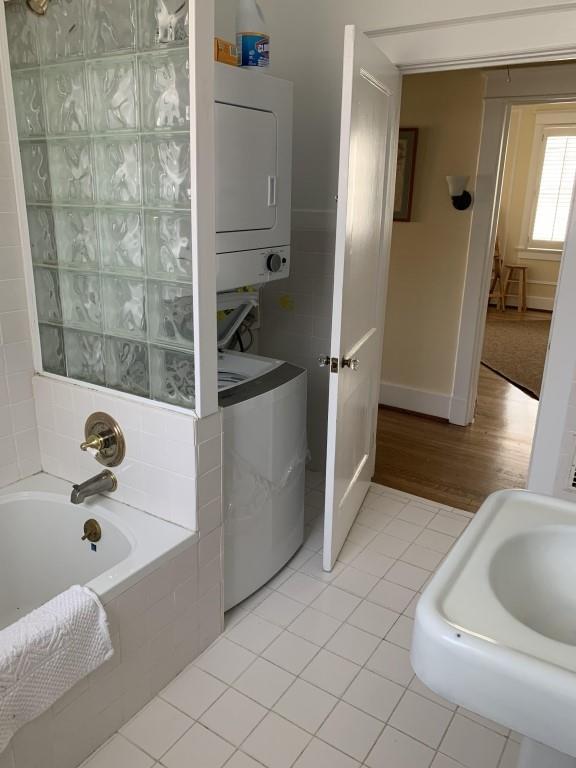 2527 Calhoun St, New Orleans, LA 70118 - full bath featuring stacked washer / drying machine, a relaxing tiled tub, and tile patterned floors