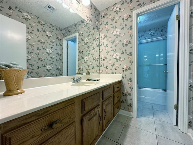 118 Golden Pheasant Dr, Slidell, LA 70461 - bathroom with wallpapered walls, a textured ceiling, vanity, tile patterned floors, and enclosed tub / shower combo
