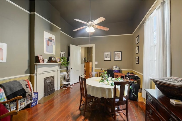 21921 Vallette St, New Orleans, LA 70114 - dining area with dark wood finished floors, a ceiling fan, a wainscoted wall, and a fireplace