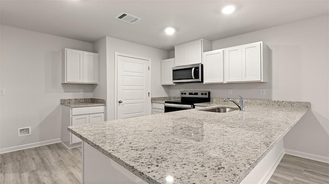 4674 Marais River Dr, Slidell, LA 70461 - kitchen with electric stove, stainless steel microwave, a peninsula, light stone counters, and light wood-type flooring
