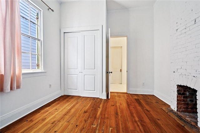 332 Olivier St, New Orleans, LA 70114 - unfurnished bedroom with wood-type flooring, a closet, and a fireplace