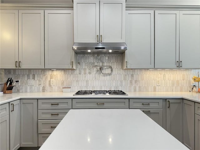 242 Douglas Dr, New Orleans, LA 70123 - kitchen with stainless steel gas stovetop, gray cabinets, under cabinet range hood, and light countertops