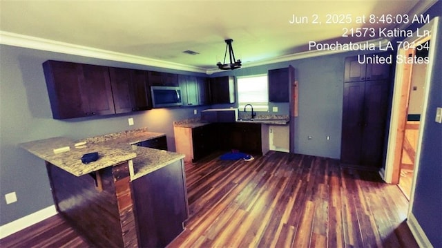 21573 Katina Ln, Ponchatoula, LA 70454 - kitchen featuring stainless steel microwave, a peninsula, dark wood-style floors, crown molding, and light stone counters
