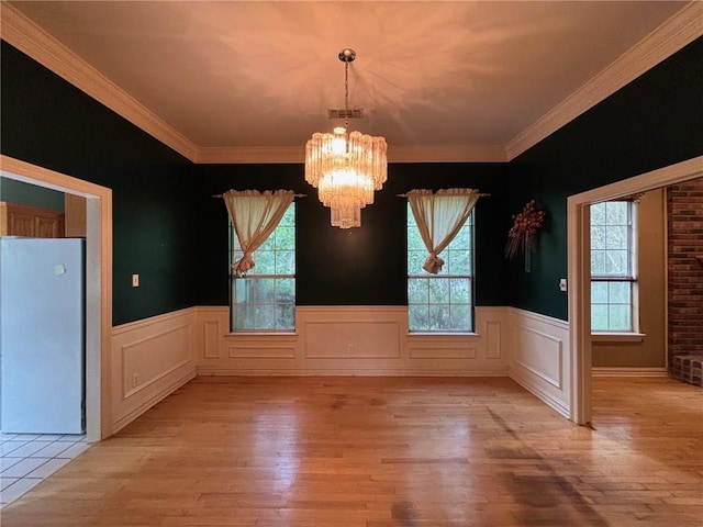 72075 Gum St, Abita Springs, LA 70420 - unfurnished dining area with a chandelier, light wood-style flooring, wainscoting, and ornamental molding