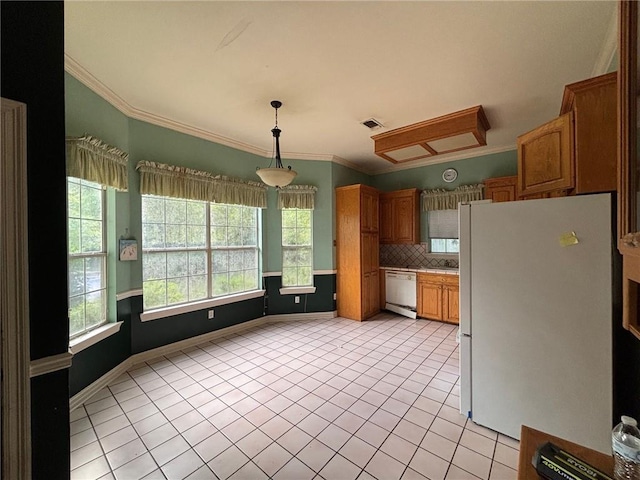 72075 Gum St, Abita Springs, LA 70420 - kitchen with white appliances, light tile patterned floors, crown molding, brown cabinets, and backsplash