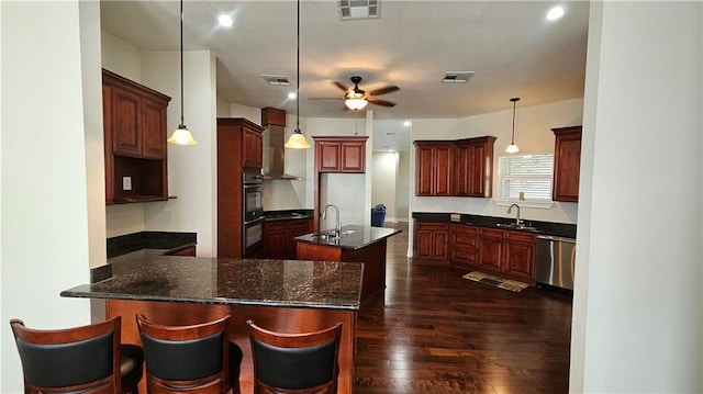 181 Latigue Rd, Avondale, LA 70094 - kitchen featuring appliances with stainless steel finishes, dark wood-style floors, ceiling fan, a peninsula, and a kitchen island with sink