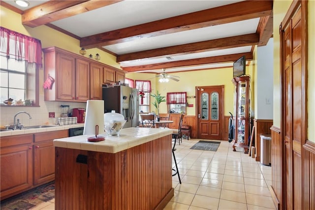 60222 N Bell Rd, Amite, LA 70422 - kitchen with tile counters, stainless steel fridge with ice dispenser, ceiling fan, a wainscoted wall, and beam ceiling