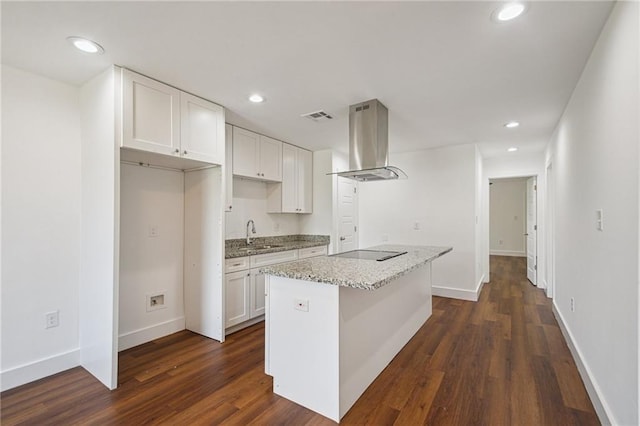3304 Metropolitan St, New Orleans, LA 70126 - kitchen with wall chimney exhaust hood, black electric cooktop, dark wood-style floors, white cabinets, and a center island