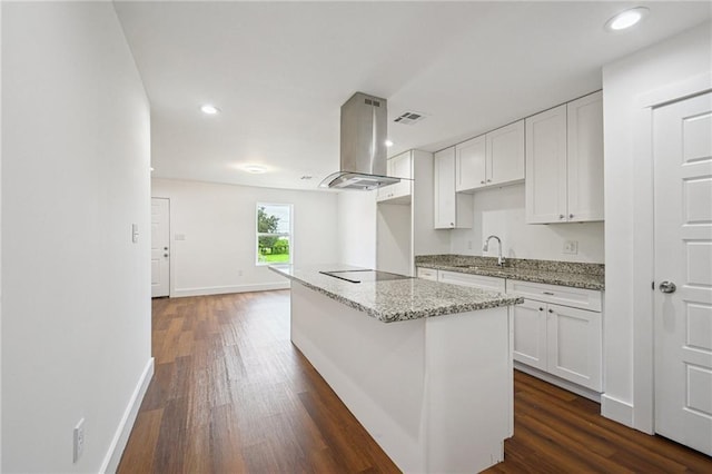 3304 Metropolitan St, New Orleans, LA 70126 - kitchen featuring island range hood, white cabinetry, dark wood-type flooring, light stone counters, and black electric cooktop